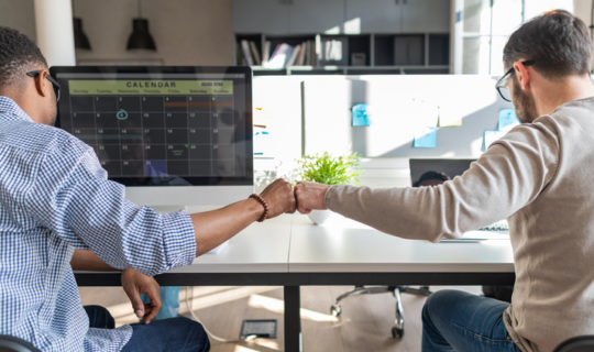 Colleagues fist bump at work