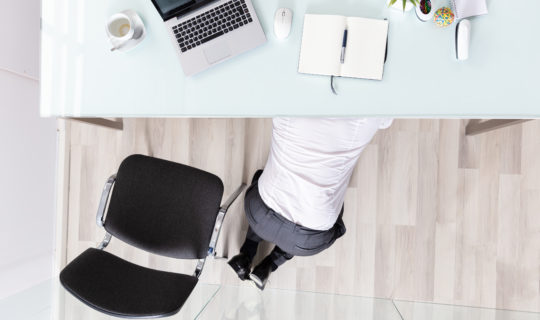 Business man hiding under desk