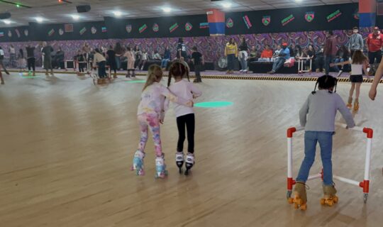 Little girl helping another little girl rollerskate