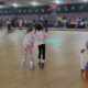 Little girl helping another little girl rollerskate