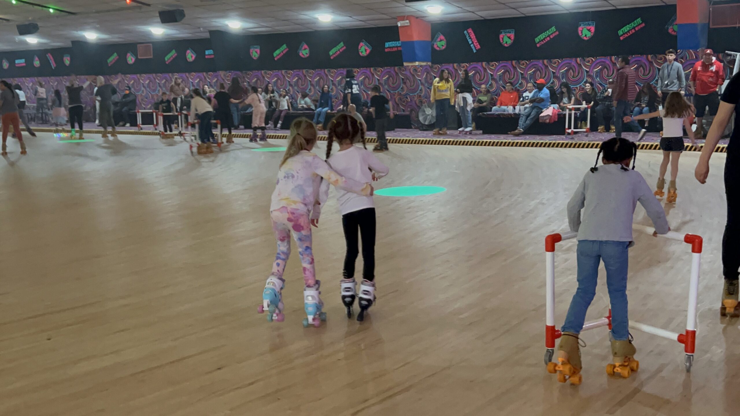 Little girl helping another little girl rollerskate